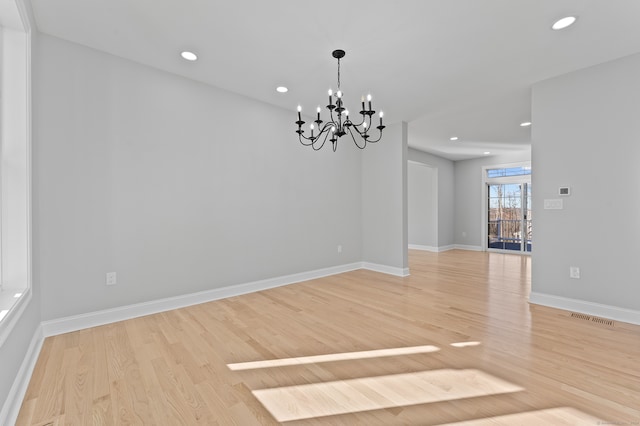 spare room with an inviting chandelier and light wood-type flooring