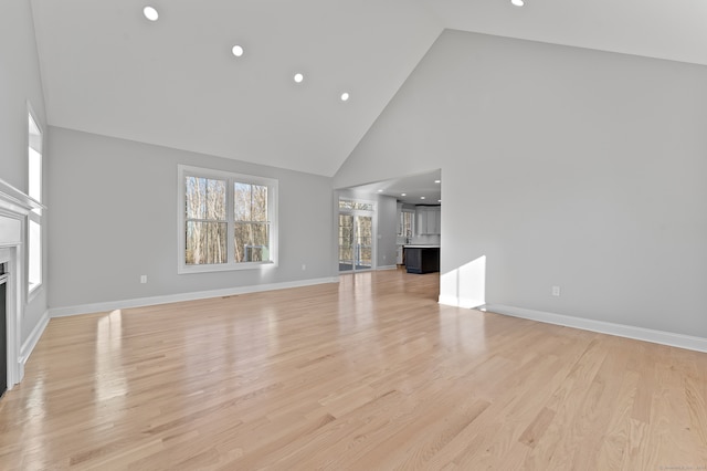 unfurnished living room featuring light wood-type flooring and high vaulted ceiling