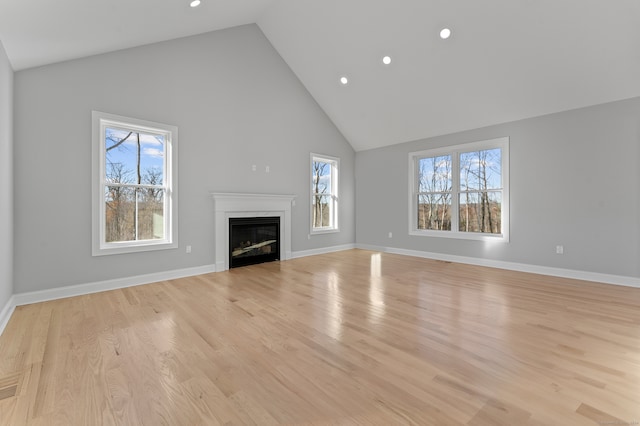 unfurnished living room featuring high vaulted ceiling, light hardwood / wood-style floors, and a wealth of natural light