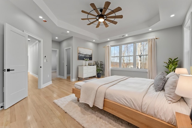 bedroom with a raised ceiling, light hardwood / wood-style flooring, and ceiling fan