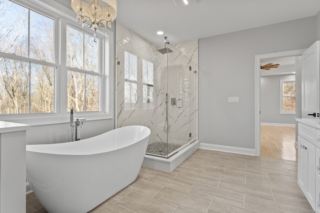 bathroom with separate shower and tub, vanity, and an inviting chandelier