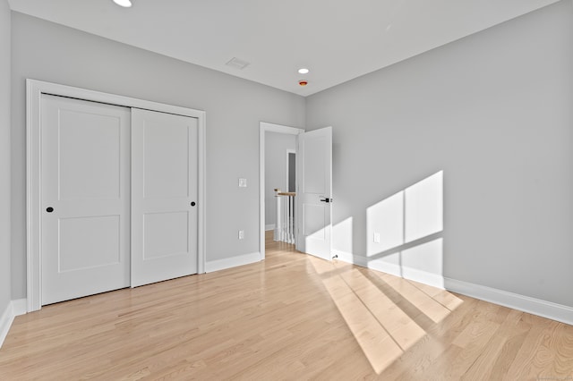 unfurnished bedroom with light wood-type flooring and a closet