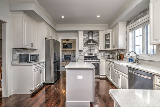 kitchen with white cabinetry, a center island, dark wood-type flooring, stainless steel appliances, and wall chimney range hood