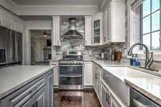 kitchen featuring appliances with stainless steel finishes, dark hardwood / wood-style flooring, white cabinetry, and wall chimney range hood