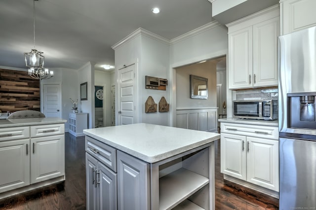 kitchen featuring appliances with stainless steel finishes, a center island, dark hardwood / wood-style floors, white cabinetry, and hanging light fixtures