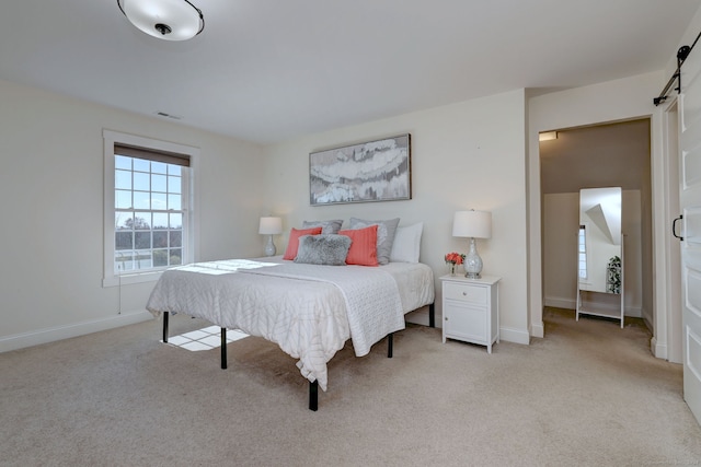 bedroom with a barn door and light carpet