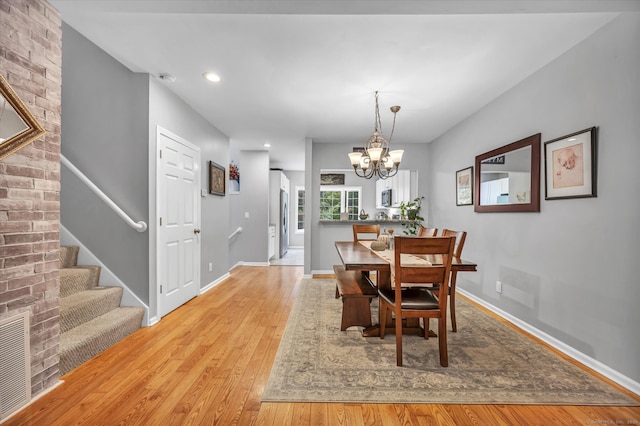 dining area with light hardwood / wood-style flooring and a notable chandelier