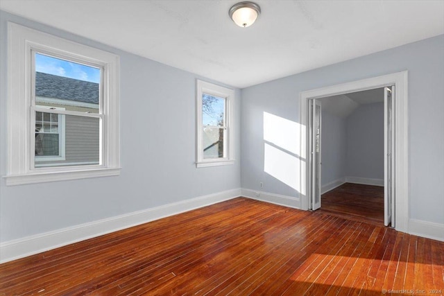 spare room featuring dark wood-type flooring and a healthy amount of sunlight