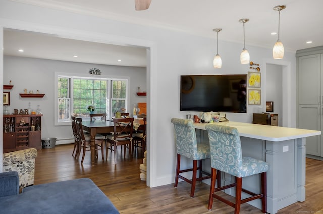 kitchen featuring a breakfast bar, dark wood-type flooring, hanging light fixtures, gray cabinets, and kitchen peninsula