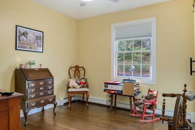 living area featuring dark hardwood / wood-style floors, ceiling fan, and a baseboard heating unit