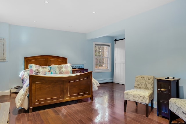 bedroom with baseboard heating, a barn door, and dark hardwood / wood-style flooring