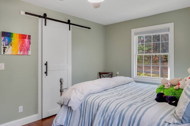 bedroom featuring a barn door, ceiling fan, and hardwood / wood-style flooring