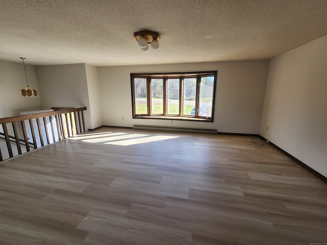 unfurnished room with a baseboard heating unit, light hardwood / wood-style flooring, and a textured ceiling