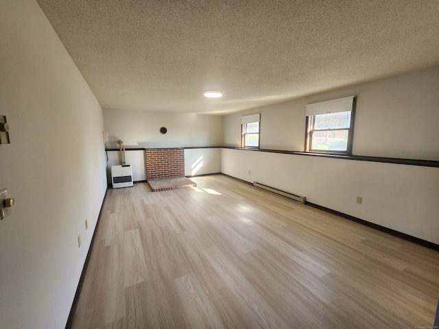 unfurnished room with baseboard heating, a textured ceiling, and light hardwood / wood-style flooring