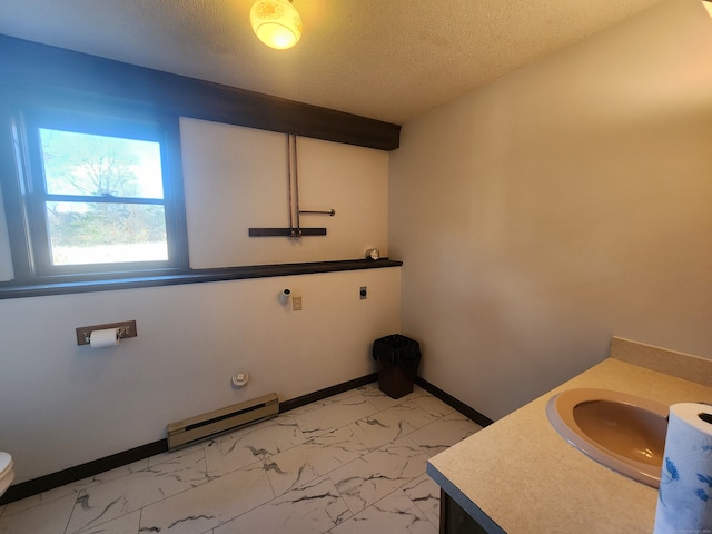 bathroom featuring toilet, vanity, a textured ceiling, and a baseboard heating unit