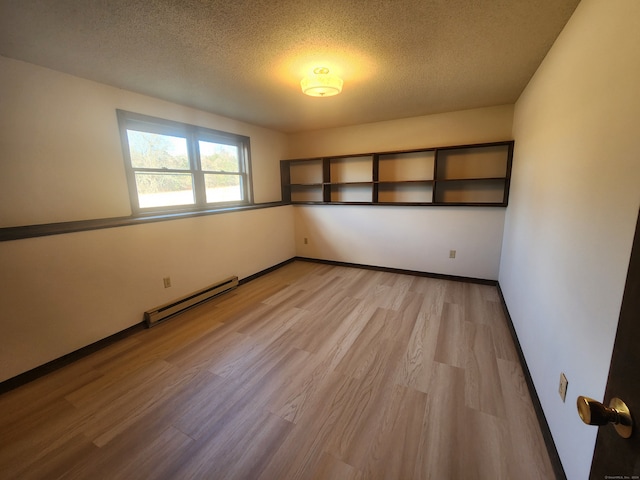 empty room featuring a baseboard heating unit, light hardwood / wood-style floors, and a textured ceiling