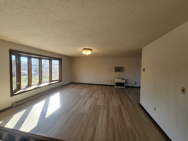 empty room with a baseboard radiator, wood-type flooring, a wall mounted AC, a textured ceiling, and heating unit