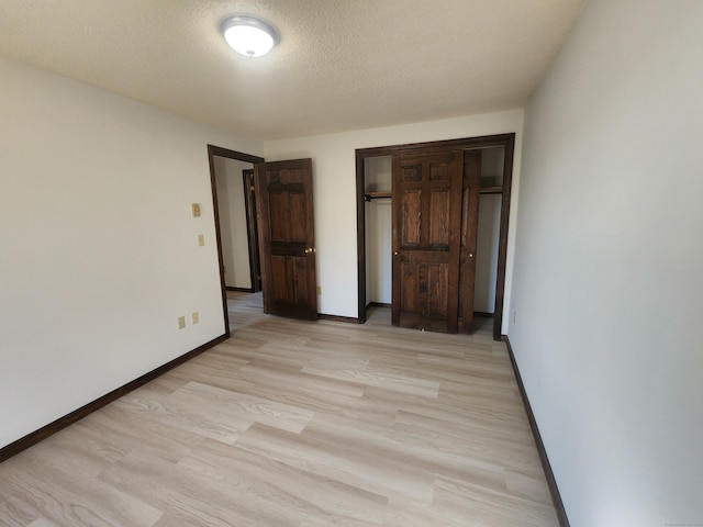 unfurnished bedroom with light hardwood / wood-style floors, a textured ceiling, and a closet