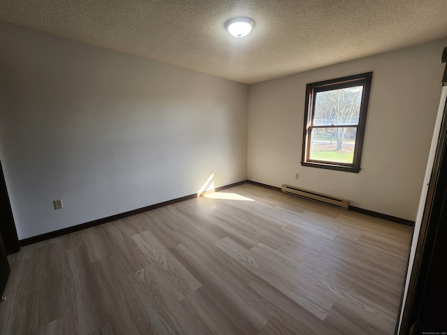 spare room with a textured ceiling, baseboard heating, and light hardwood / wood-style floors