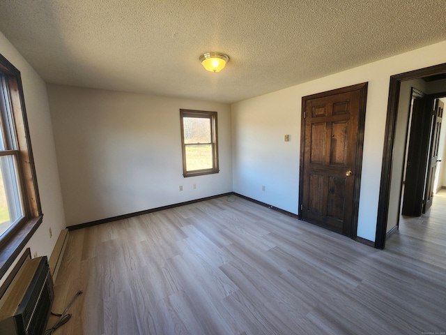 unfurnished room featuring a wall mounted AC, light hardwood / wood-style floors, and a textured ceiling