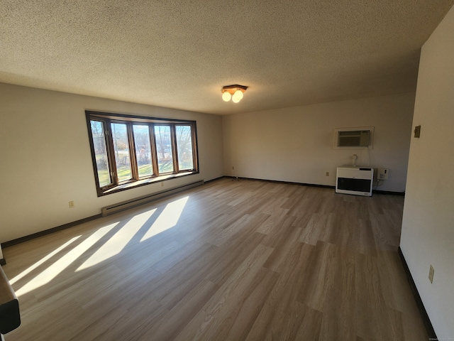 interior space featuring a baseboard heating unit, a wall unit AC, hardwood / wood-style floors, a textured ceiling, and heating unit