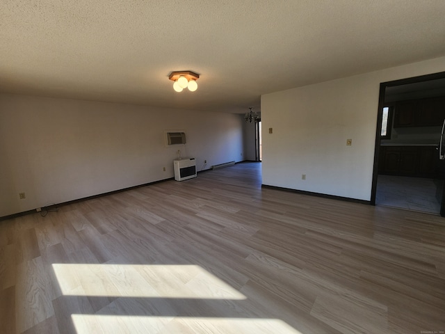 empty room with light hardwood / wood-style flooring, a textured ceiling, and heating unit