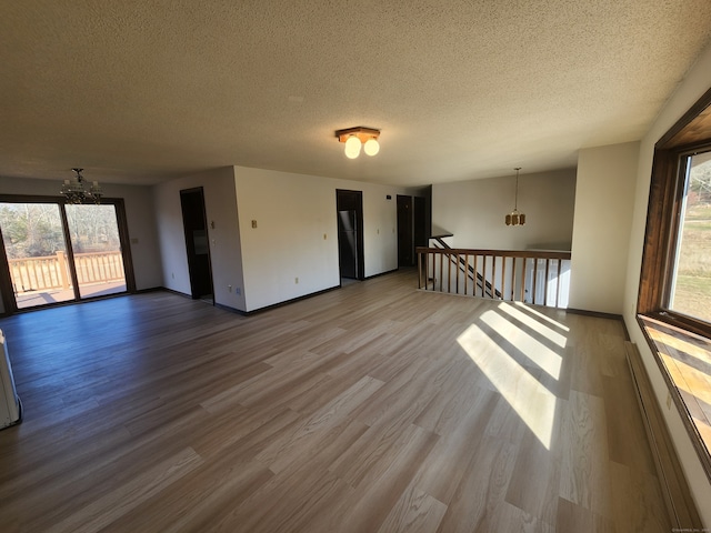 unfurnished room featuring a textured ceiling, hardwood / wood-style flooring, and an inviting chandelier