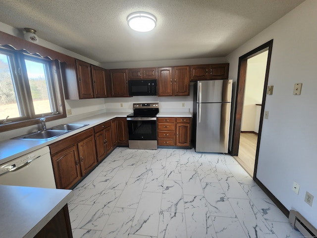 kitchen featuring a textured ceiling, sink, baseboard heating, dark brown cabinets, and appliances with stainless steel finishes