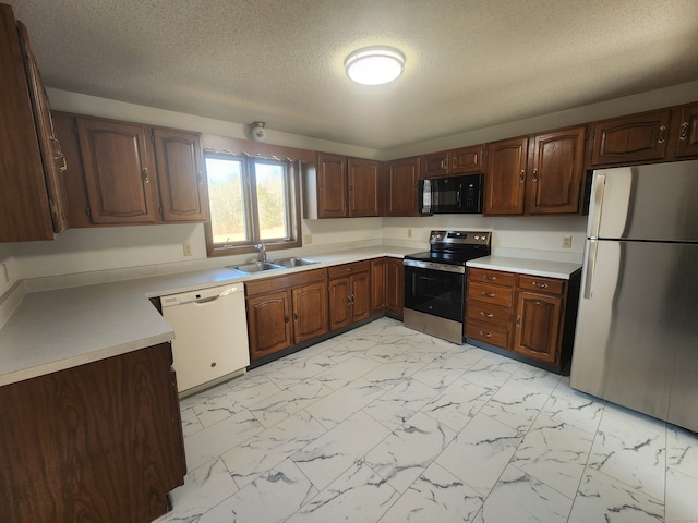 kitchen featuring a textured ceiling, sink, dark brown cabinets, and stainless steel appliances