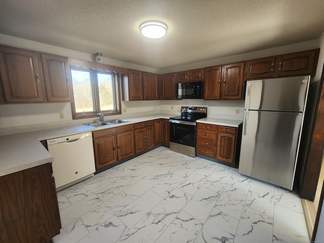 kitchen featuring stainless steel appliances, a textured ceiling, sink, and dark brown cabinetry