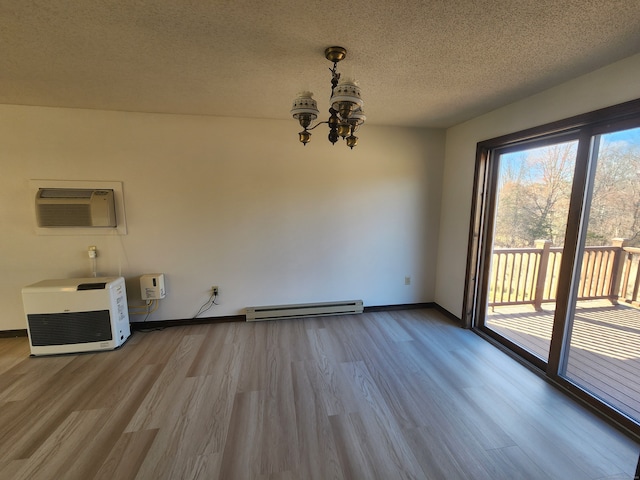 unfurnished dining area featuring a textured ceiling, an inviting chandelier, hardwood / wood-style floors, a baseboard radiator, and an AC wall unit