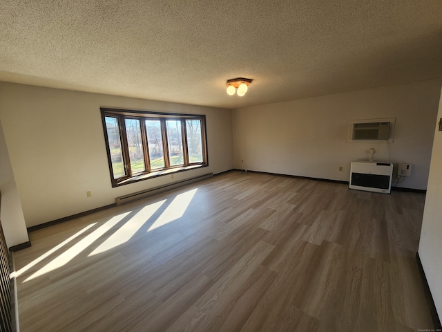 unfurnished living room featuring baseboard heating, heating unit, a textured ceiling, wood-type flooring, and an AC wall unit