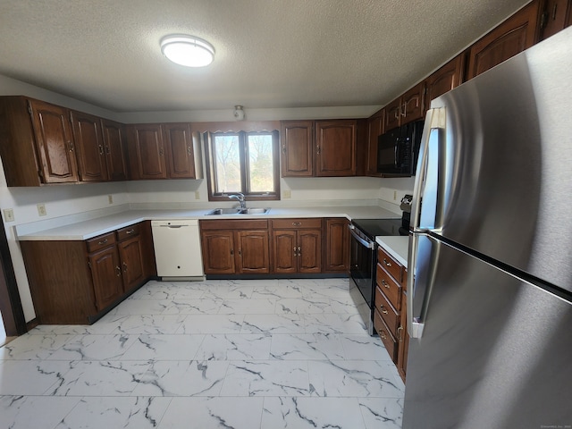 kitchen featuring a textured ceiling, appliances with stainless steel finishes, sink, and dark brown cabinets