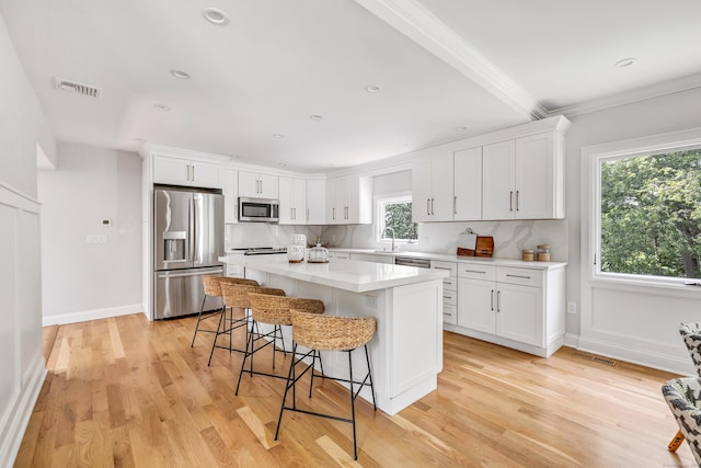 7 Topping Ln, Norwalk, CT 06854 - kitchen featuring stainless steel appliances, a breakfast bar area, a kitchen island, white cabinets, and ornamental molding