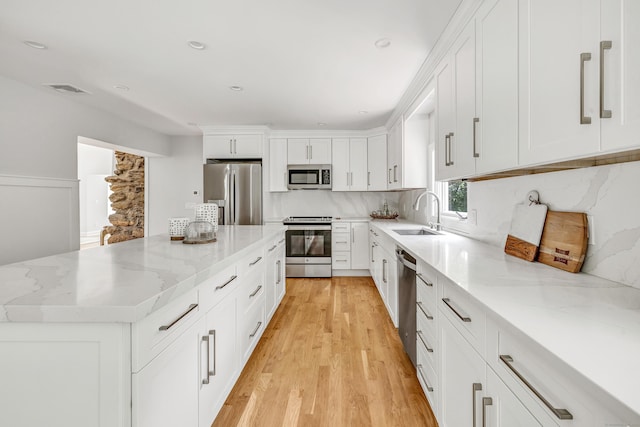 7 Topping Ln, Norwalk, CT 06854 - kitchen featuring stainless steel appliances, a sink, light wood-style flooring, a center island, and white cabinetry