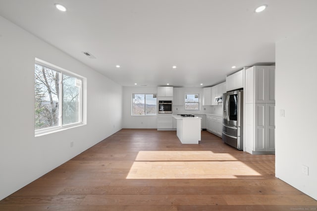 kitchen featuring a center island, light wood-type flooring, white cabinetry, and stainless steel appliances