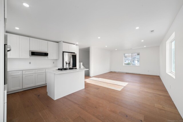 kitchen featuring a center island, white cabinets, stainless steel appliances, and light hardwood / wood-style floors