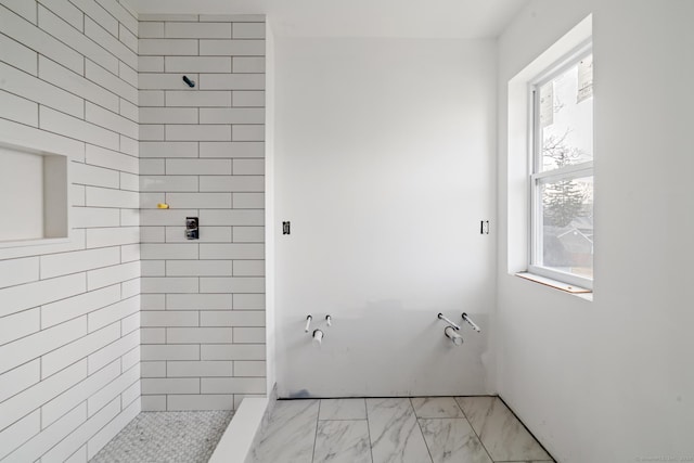 bathroom with a tile shower and plenty of natural light