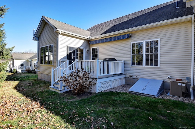 rear view of house featuring a wooden deck and a lawn