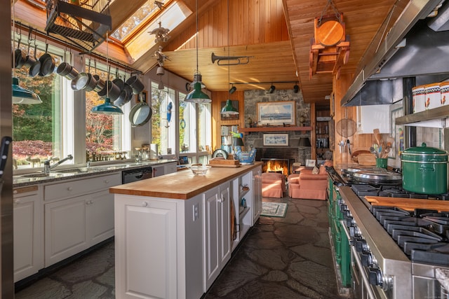 kitchen featuring wood walls, sink, wooden counters, a kitchen island, and white cabinets