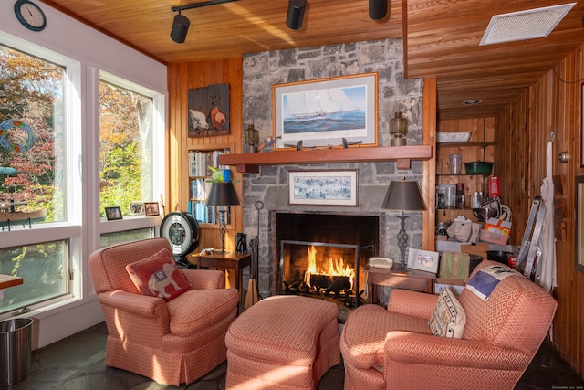 sitting room featuring wooden ceiling, a fireplace, wooden walls, and carpet floors