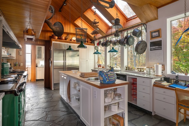 kitchen featuring wood ceiling, wooden walls, a skylight, a kitchen island, and white cabinetry