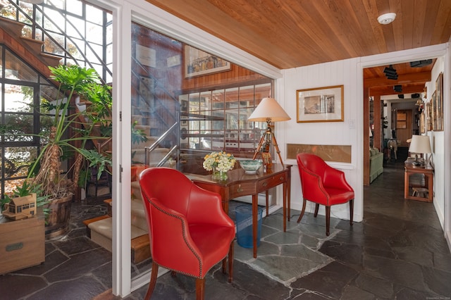 living area with wood ceiling, wooden walls, and a healthy amount of sunlight