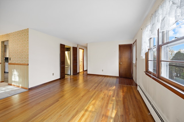 unfurnished room featuring hardwood / wood-style flooring and a baseboard heating unit