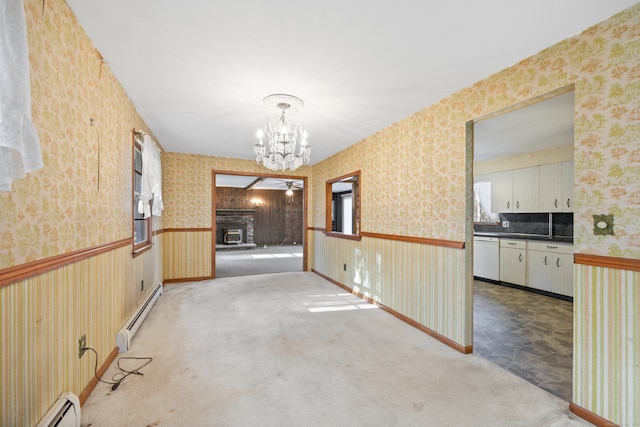 carpeted spare room featuring a chandelier, a healthy amount of sunlight, and a baseboard heating unit