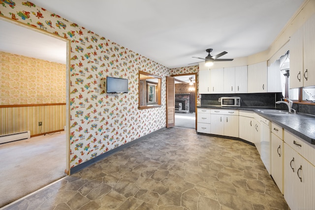 kitchen with a fireplace, sink, ceiling fan, and dark carpet