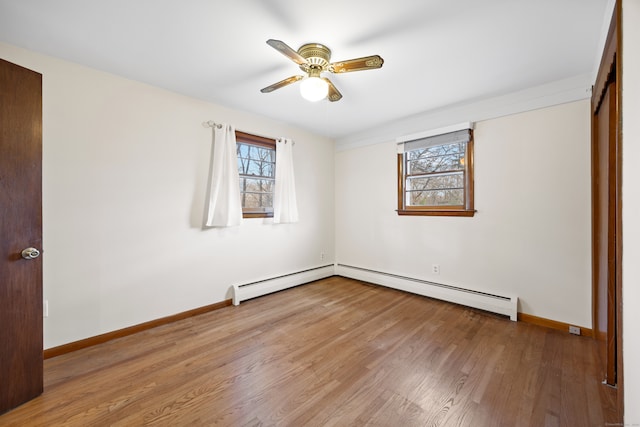 unfurnished bedroom featuring a baseboard heating unit, wood-type flooring, multiple windows, and ceiling fan