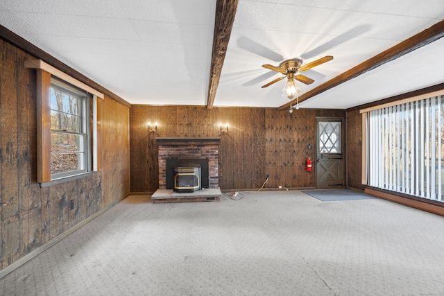 unfurnished living room with a wood stove, wood walls, beamed ceiling, and light carpet