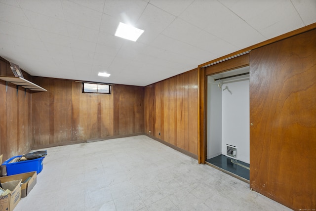 basement featuring wooden walls and heating unit