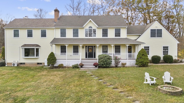 colonial-style house featuring covered porch and a front yard